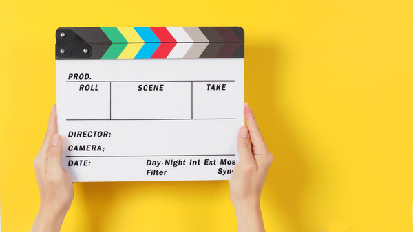 hands holding a clapperboard behind a bright yellow backdrop Filmmaking Planner 