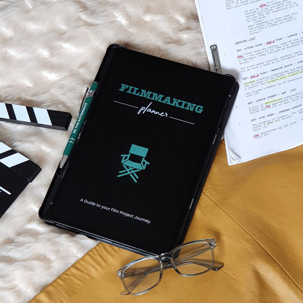 Green digital filmmaking planner on IPad next to script and glasses 